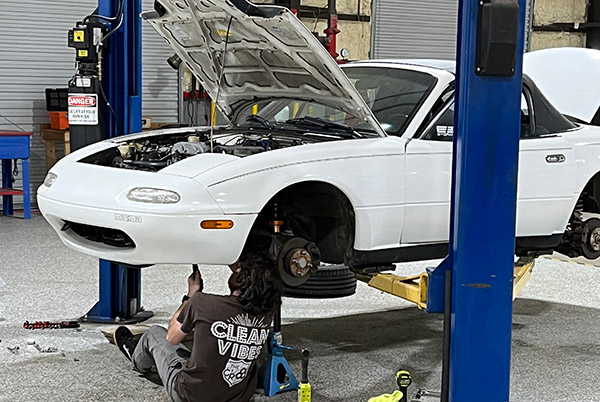 Car lift with Mazda Miata on it.